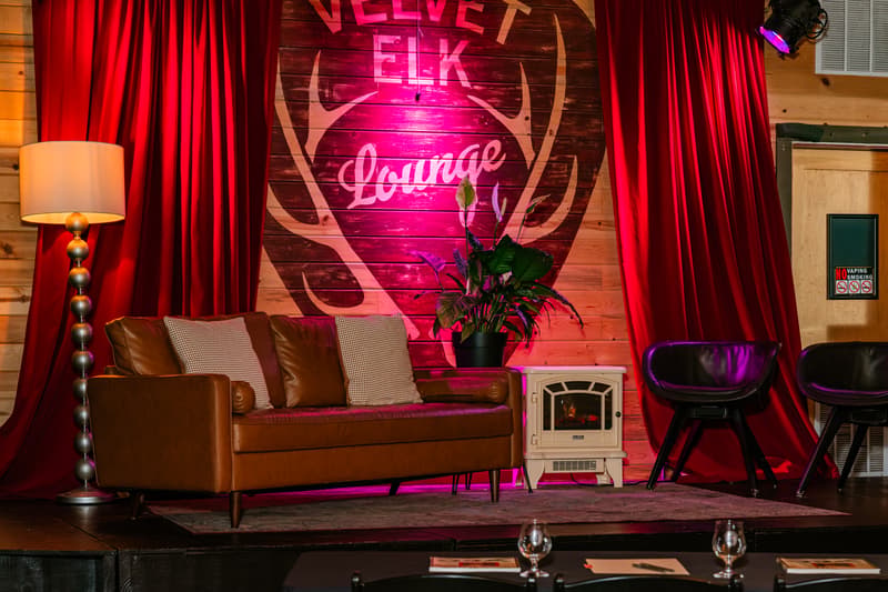 Empty stage with red curtains, sofa and lit Velvet Elk Lounge sign