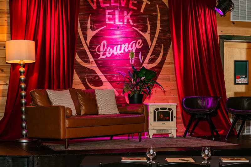 Empty stage with red curtains, sofa and lit Velvet Elk Lounge sign