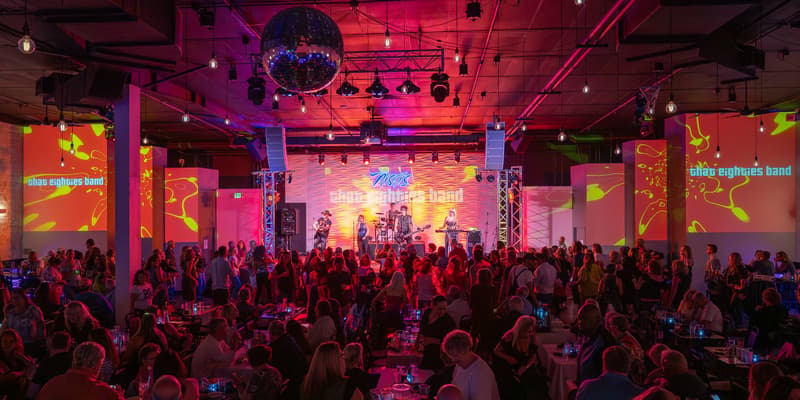 Crowd at tables watching a band under a disco ball