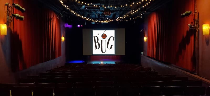 Empty seats facing the stage with red curtains and string lights